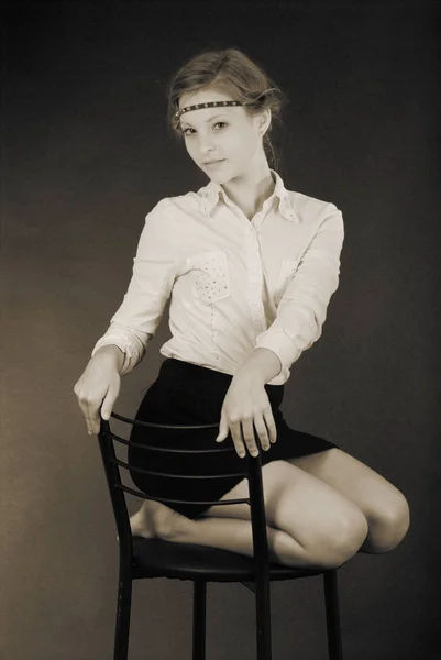 Νεαρό κορίτσι που κάθεται σε μια καρέκλα — Φωτογραφία Αρχείου