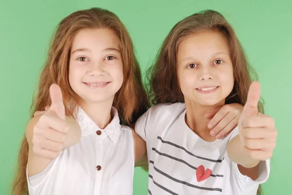 Two smiling young school girls showing thumbs up