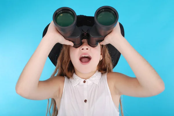 Beautiful young girl  looking through binoculars with surprised expression — Stock Photo, Image
