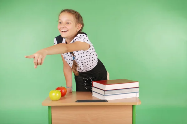 Девушка в школьной форме сидит за столом и показывает — стоковое фото