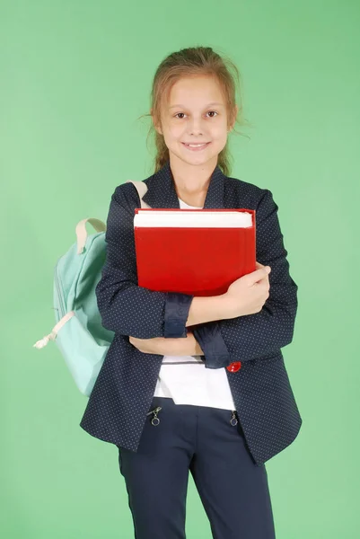 Menina da escola jovem com livro vermelho e mochila — Fotografia de Stock