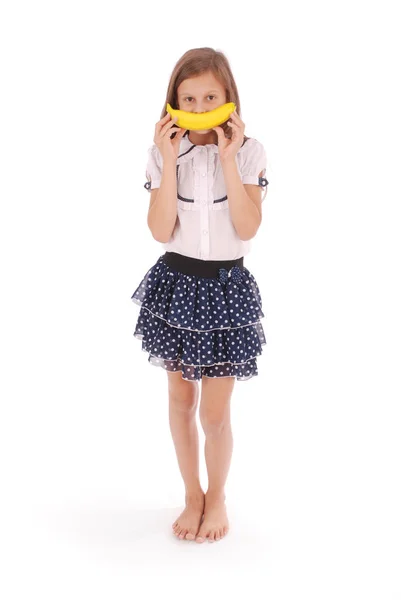 Menina segura uma banana na boca, imitando um sorriso — Fotografia de Stock
