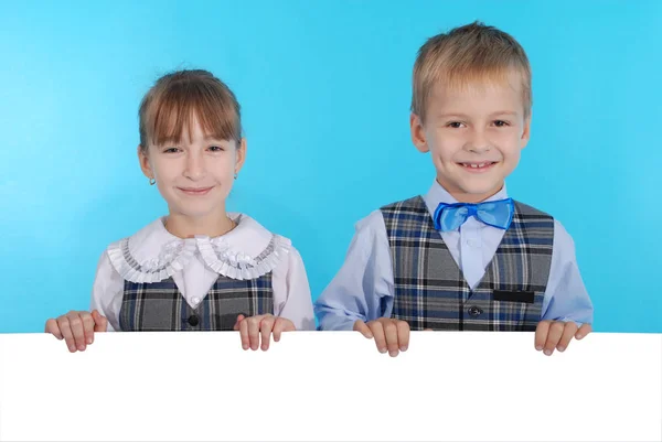 Boy and girl smiling and holding a white banner — Stock Photo, Image