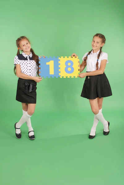 Två skolflickor hålla färg board med nummer arton — Stockfoto