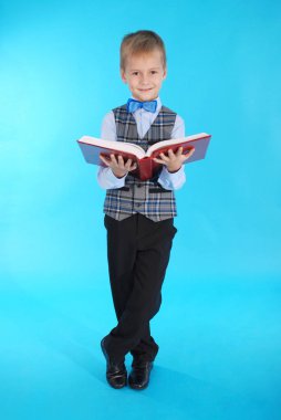 Açık bir kırmızı kitap tutan okul üniformalı çocuk