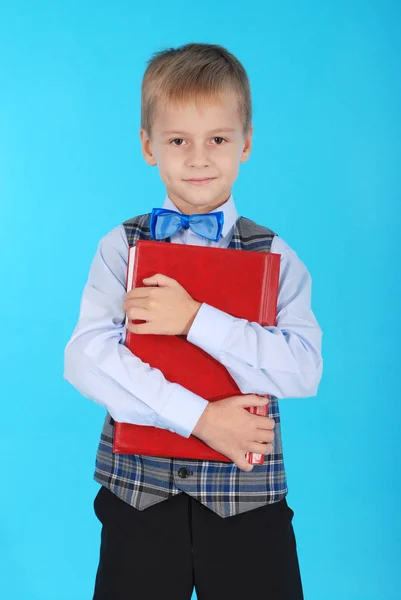 Garçon en uniforme scolaire tenant un livre rouge — Photo
