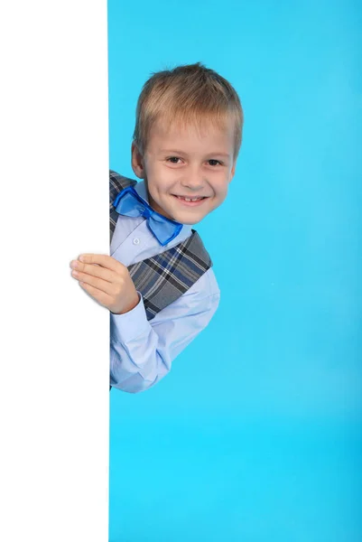 Beyaz bir reklam panosunun arkasına poz gülümseyen bir okul çocuğu — Stok fotoğraf