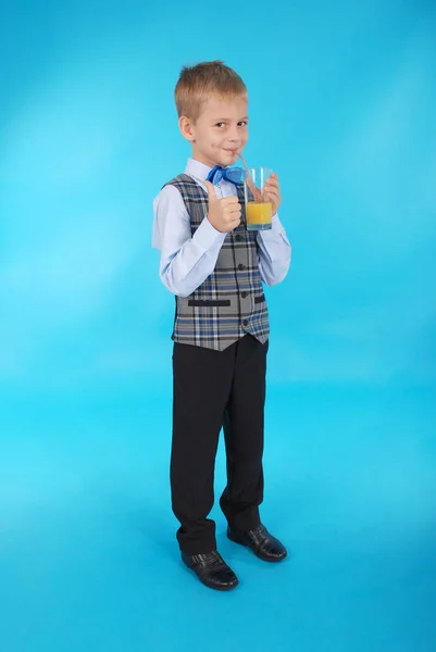 Хлопчик п'є апельсиновий сік і показує великий палець вгору — стокове фото