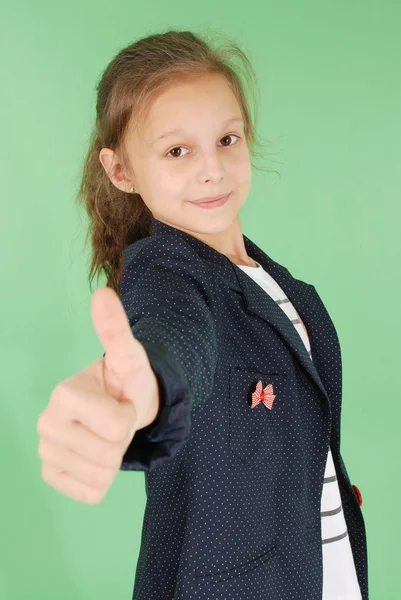 Улыбающаяся школьница показывает большие пальцы вверх — стоковое фото