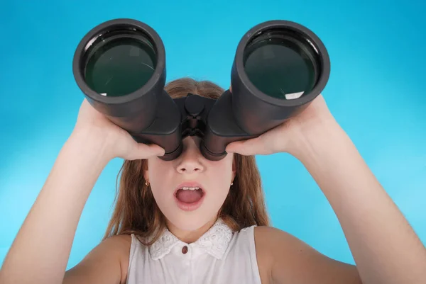 Beautiful young girl  looking through binoculars with surprised expression — Stock Photo, Image