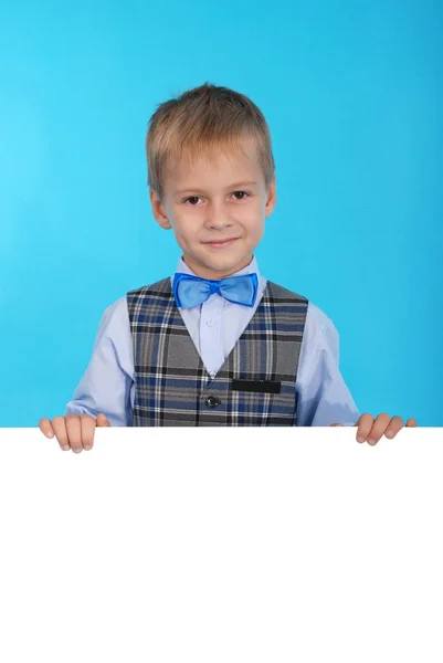 Beyaz bir reklam panosunun arkasına poz gülümseyen bir okul çocuğu — Stok fotoğraf