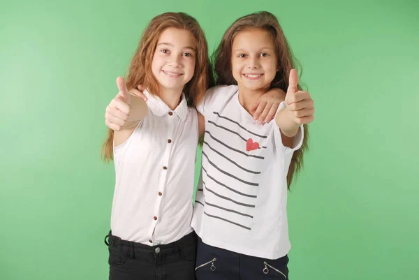 Дві усміхнені молоді школярки показують великі пальці вгору — стокове фото