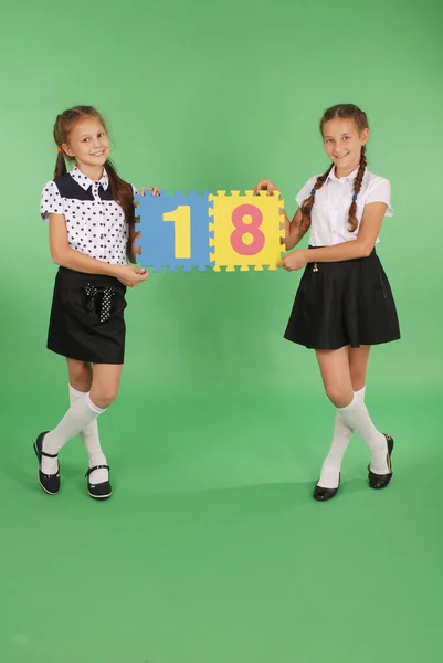Två skolflickor hålla färg board med nummer arton — Stockfoto
