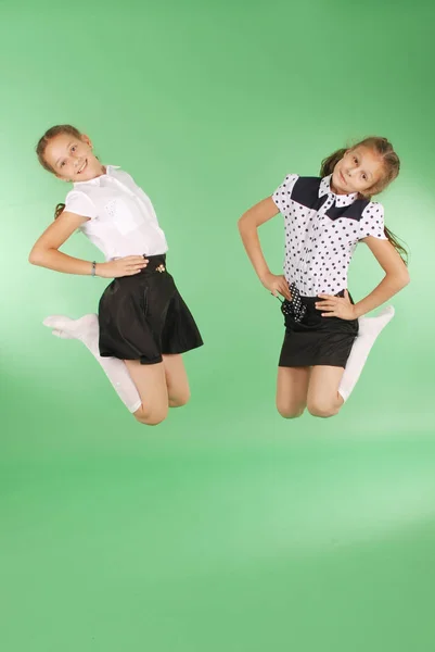Cute happy school girls jumping