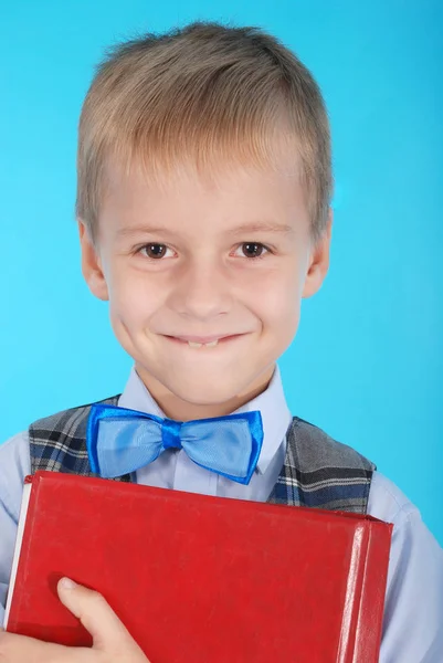 Portrait of a boy in school uniform who holds the red book — Stock Photo, Image