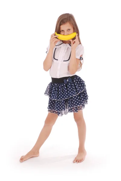 Menina segura uma banana na boca, imitando um sorriso — Fotografia de Stock