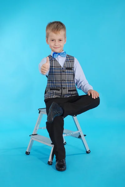 Schooljongen zittend op een trapladder en duimen opdagen — Stockfoto