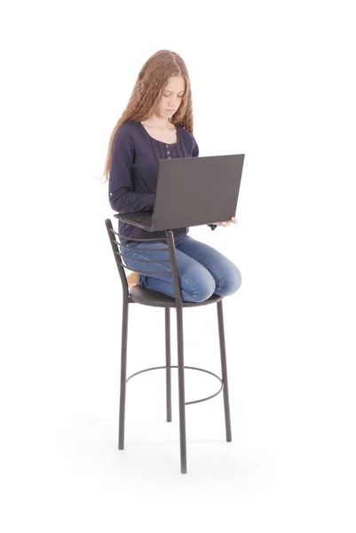 Dívka sedí na židli a držení notebooku — Stock fotografie