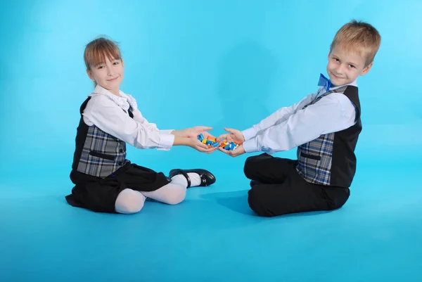 Schoolboy and schoolgirl playing with candy — Stock Photo, Image