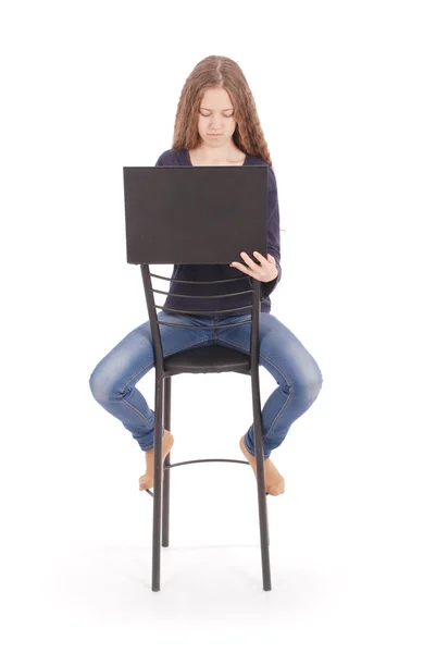 Chica se sienta en una silla y la celebración de un ordenador portátil —  Fotos de Stock