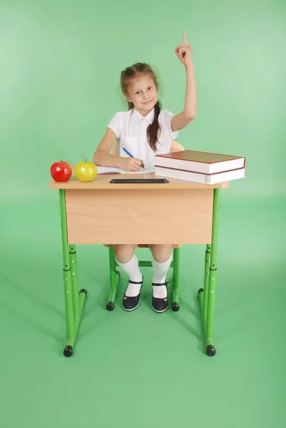 Девушка в школьной форме поднимает руку, чтобы задать вопрос — стоковое фото