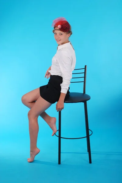 Giovane ragazza si siede su una sedia — Foto Stock