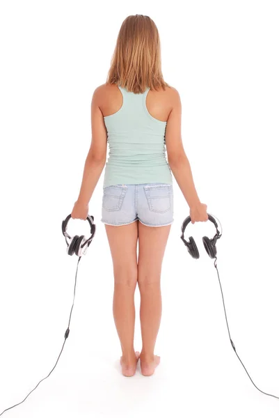 Teenage girl is standing back in the hands holding headphones — Stock Photo, Image