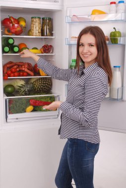 Dolgulu buzdolabı yakınındaki memnun ev kadını.
