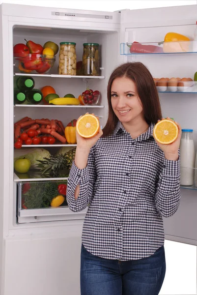 Hermosa joven cerca del refrigerador con comida saludable . — Foto de Stock