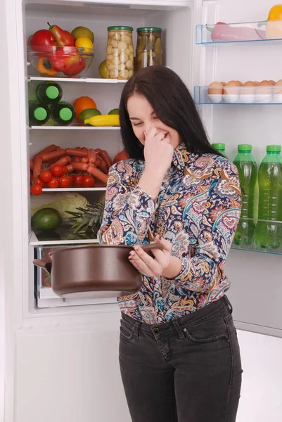 Irritada e chateada dona de casa olhando para um pote com refeição suja — Fotografia de Stock