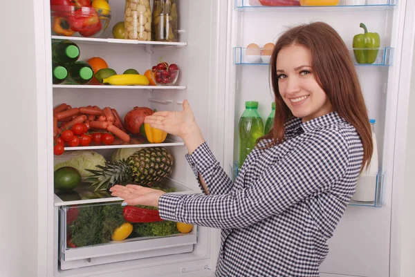 Satisfeito dona de casa perto da geladeira cheia . — Fotografia de Stock