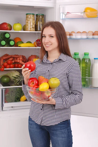 Beautiful young girl near the Fridge with healthy food.