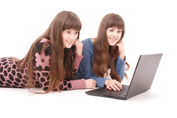 Портрет двух сестер близнецов с ноутбуком — стоковое фото
