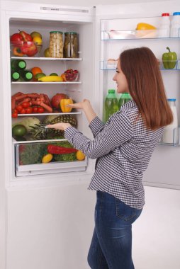 Dolgulu buzdolabı yakınındaki memnun ev kadını.