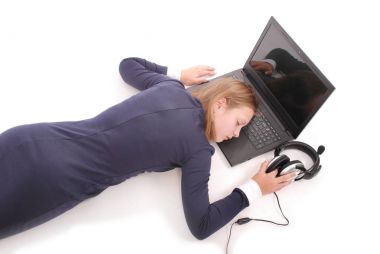 Sevimli genç uyuyan kız görüntüsünü kulaklık dizüstü bilgisayarın yakınında yatıyor