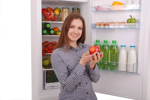 Hermosa joven cerca del refrigerador con comida saludable . — Foto de Stock