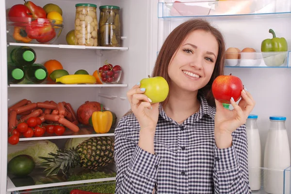Mooi jong meisje in de buurt van de koelkast met gezonde voeding. — Stockfoto