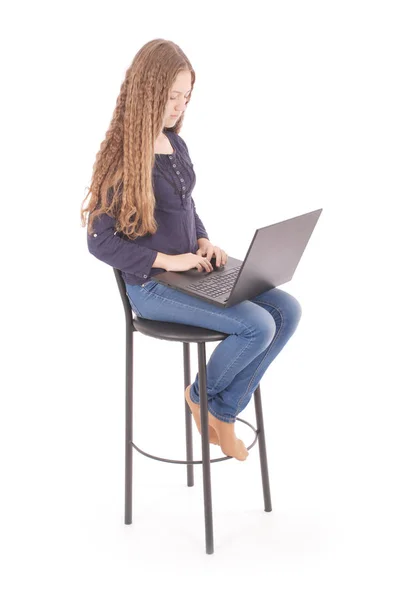 Mädchen sitzt auf einem Stuhl und hält einen Laptop — Stockfoto