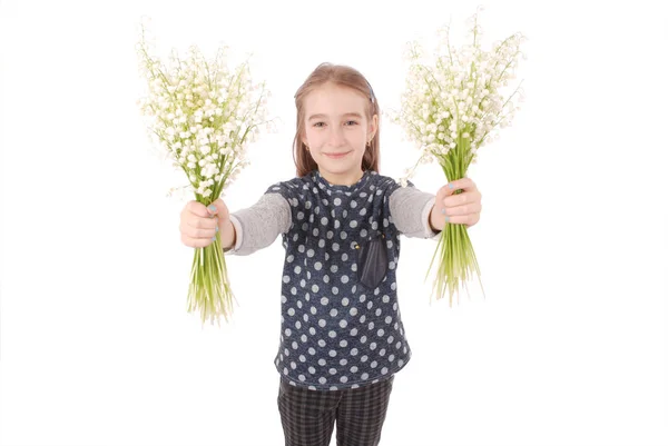 Retrato de una linda niña feliz sostiene una flor de un lirio del valle . — Foto de Stock