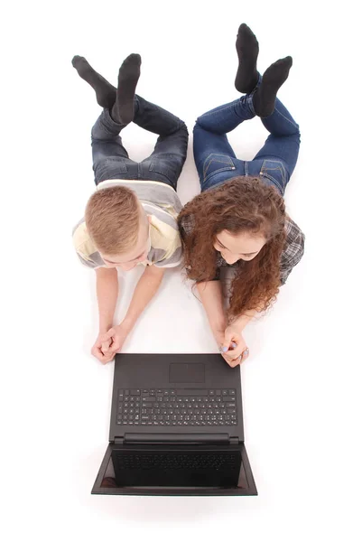Boy and girl using a laptop lying on the floor — Stock Photo, Image