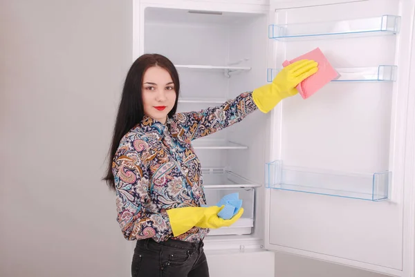 若い女の子のスポンジで空の冷蔵庫を掃除. — ストック写真