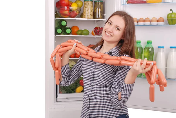 Genç kız sosis buzdolabı arka plan üzerinde tutar.