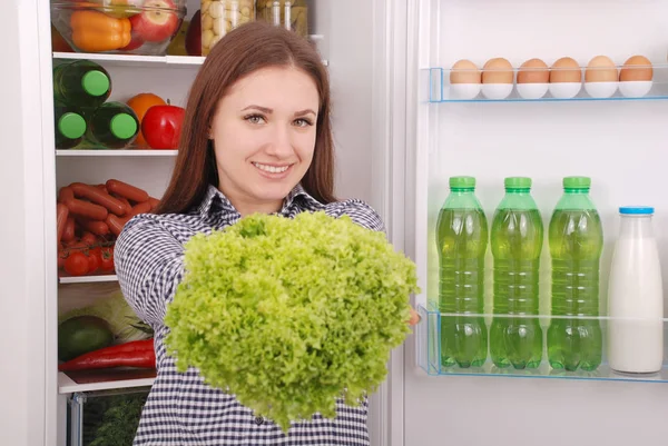 Hermosa joven cerca del refrigerador con comida saludable . — Foto de Stock