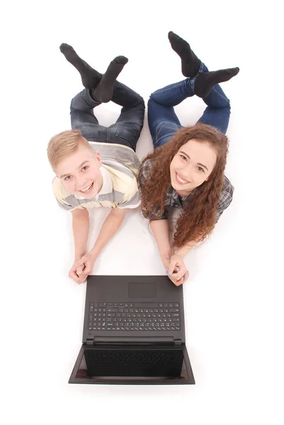 Boy and girl using a laptop lying on the floor — Stock Photo, Image