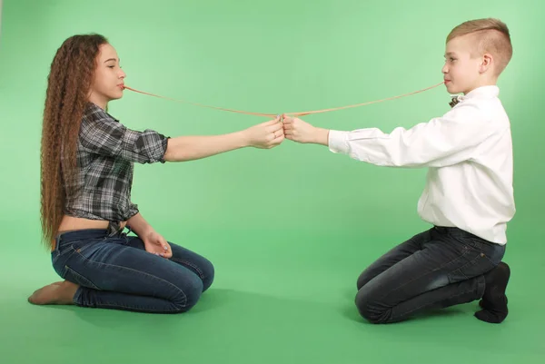 Young boy and girl stretching from chewing gum which he carries in his mouth — Stock Photo, Image