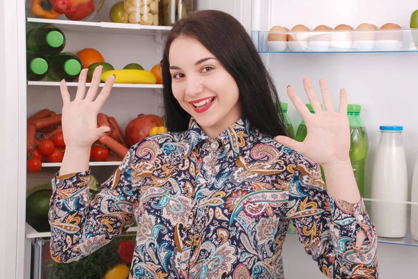 Satisfied housewife near filled fridge. — Stock Photo, Image