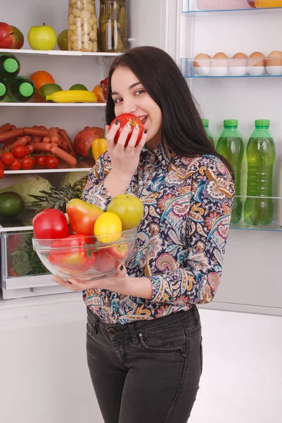 Beautiful young girl near the Fridge with healthy food.