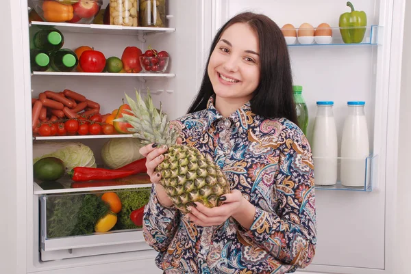 Mooi jong meisje in de buurt van de koelkast met gezonde voeding. — Stockfoto