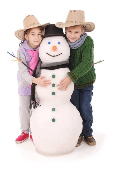 Aranyos fiú és a lány kalap és sál hóember — Stock Fotó