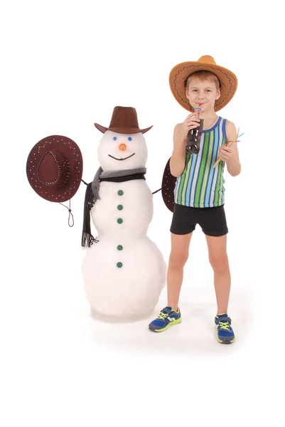 Sevimli çocuk atkı ve şapka ile bir kardan adam yakınındaki bir kola şişesi holding — Stok fotoğraf